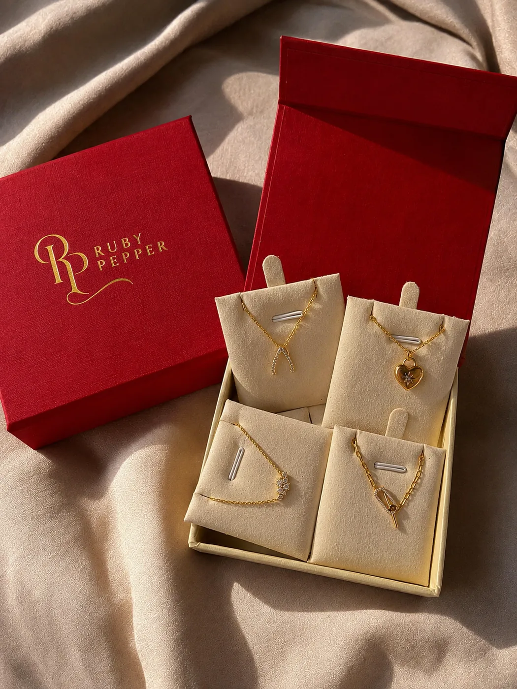 Ruby velvet jewellery gift box tied with a soft gold ribbon on ivory linen